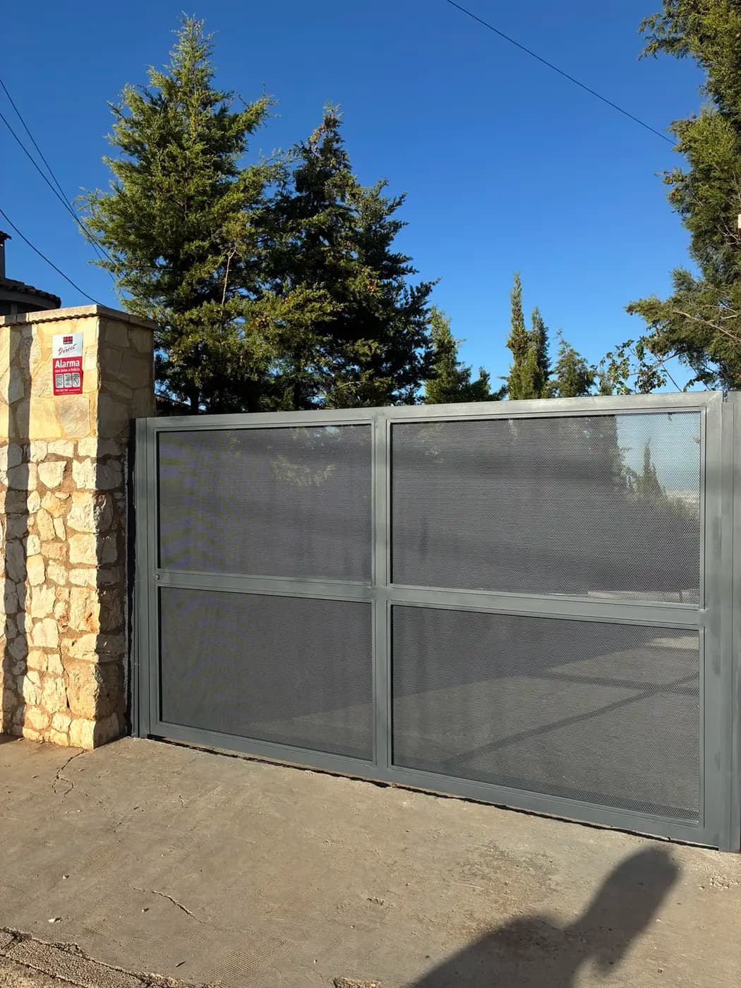 Cancela metálica batiente gris instalada en vivienda