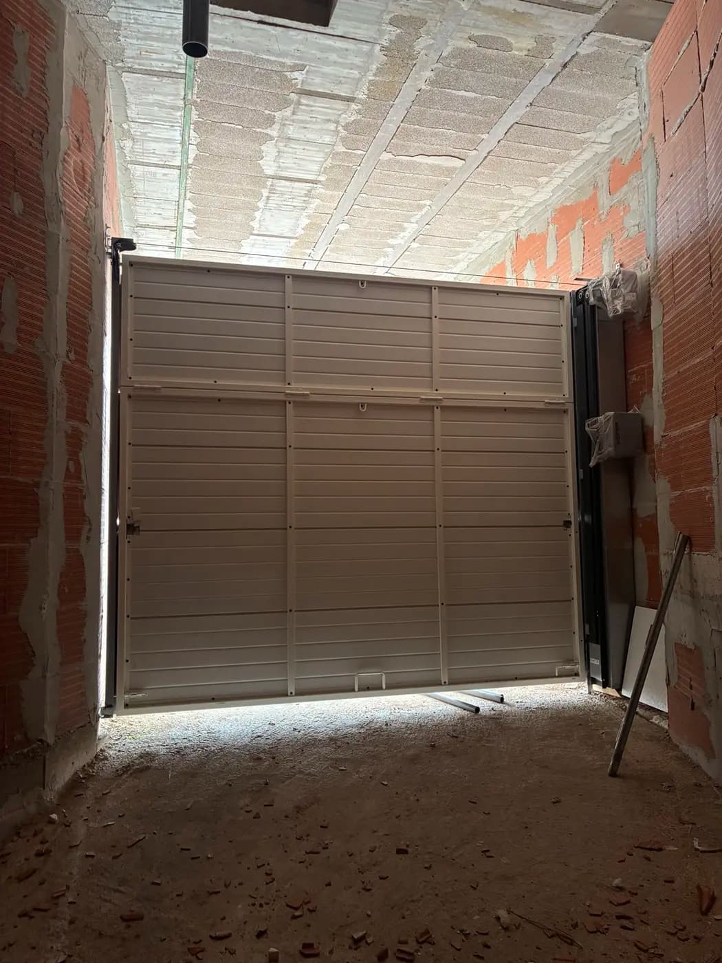 Vista interior de una puerta blanca de apertura vertical tipo guillotina
